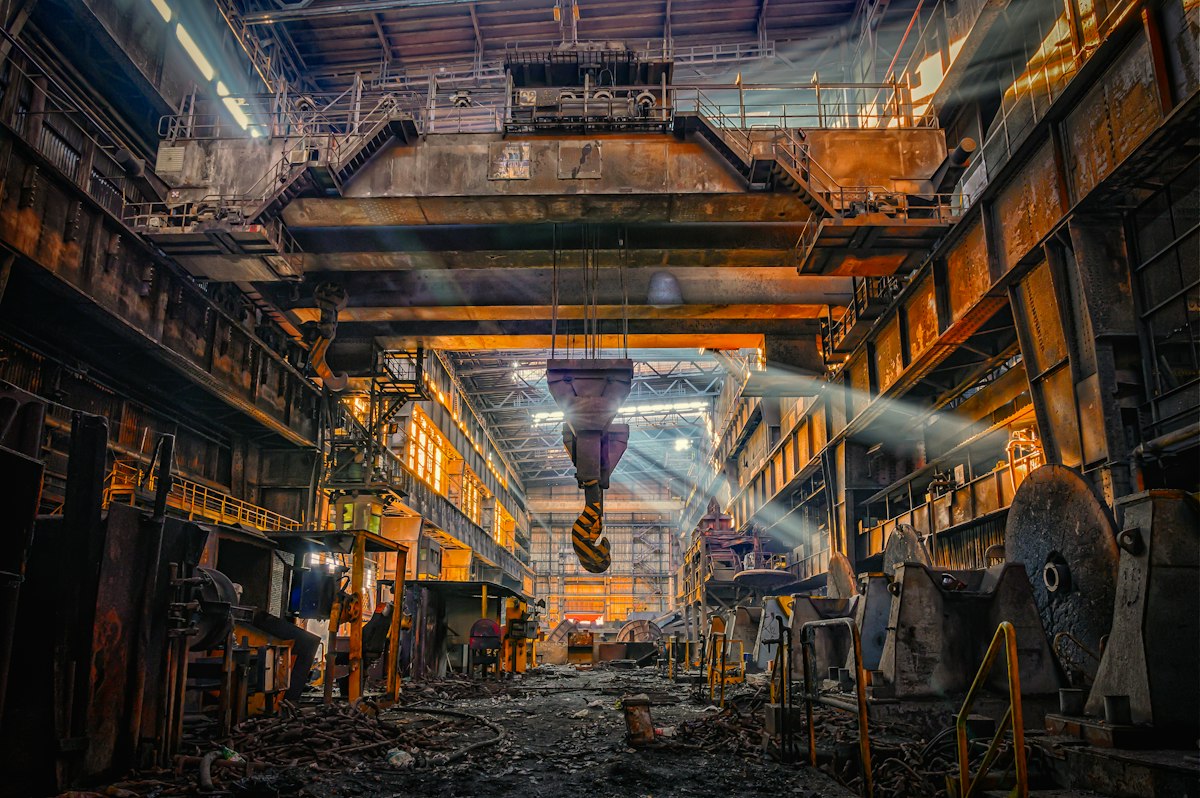 Robotic arms guiding glowing steel billets along a conveyor inside a modern rolling mill.